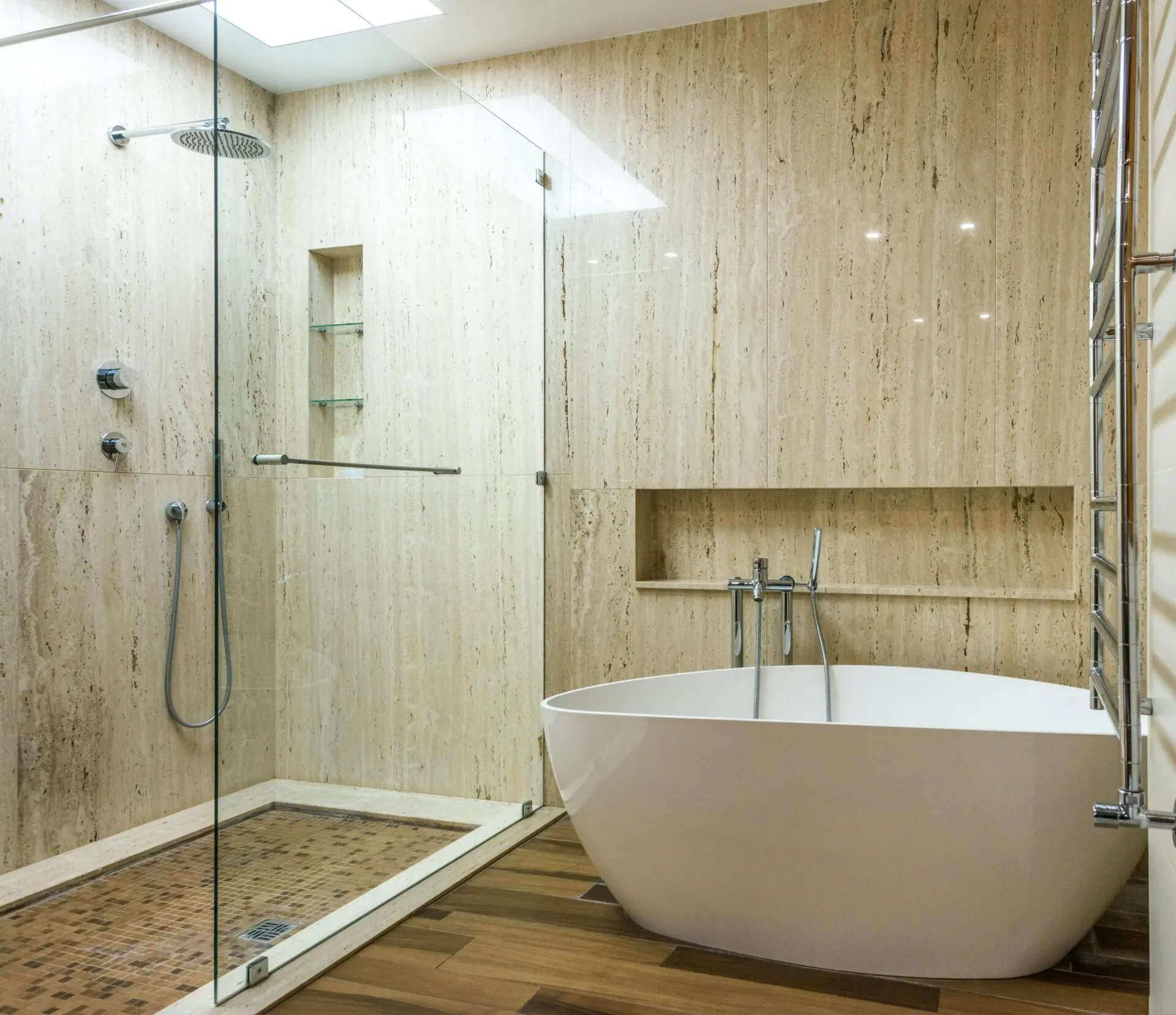 Contemporary bathroom featuring a marble wall, glass shower, and stylish bathtub.